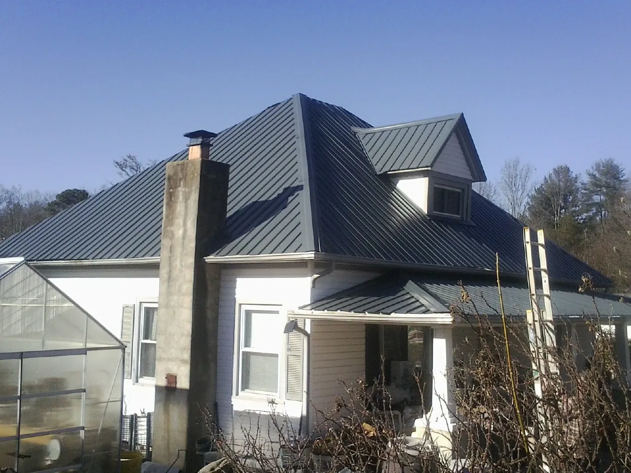 Dark blue standing seam metal roof on a white farmhouse with dormer — Slate & Tile Roof Repair by Roofing Brothers in Erwinna