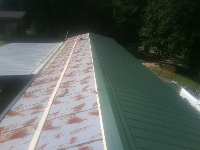 Old rusted panels beside newly installed green metal roofing — Wind Damage Roof Repair by Roofing Brothers in Erwinna