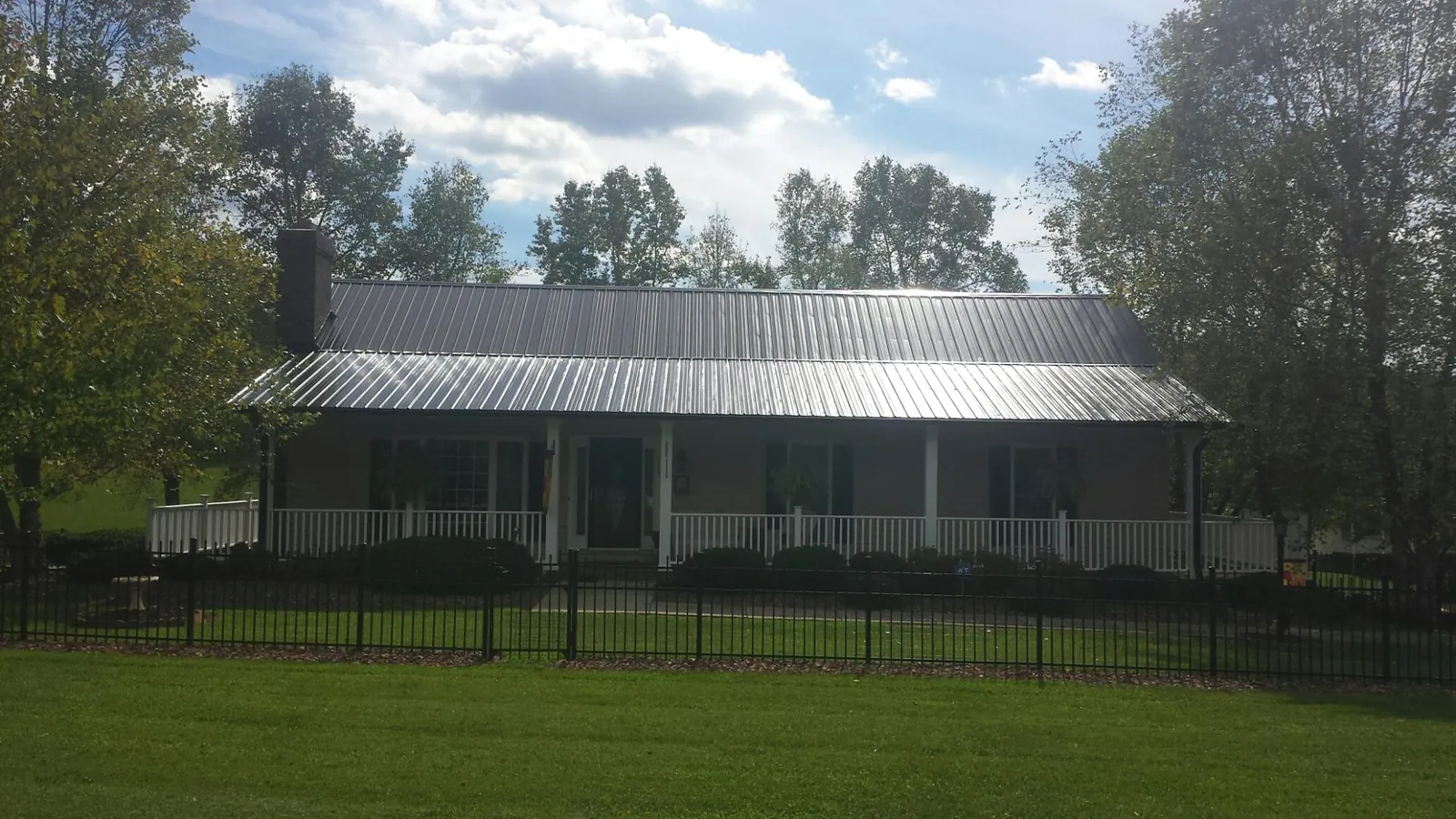 Gray metal roof on a brick ranch with a full width front porch — Gutter Guard Installation work by our crew in Erwinna