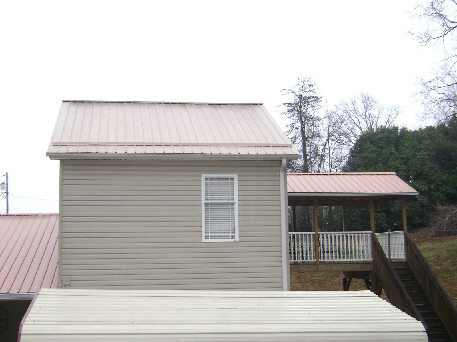 Tan metal roofs on a two story addition and attached porch, from a Roof Replacement job in Erwinna